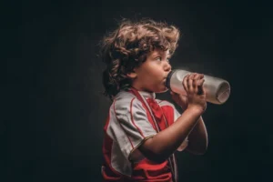 jongen in sportkleding met gouden medaille drinkt water uit een fles